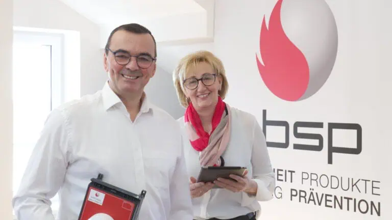 Informatiker bei i-bsp präsentieren innovative Brandschutzlösungen mit Tablet und digitalen Produkten.