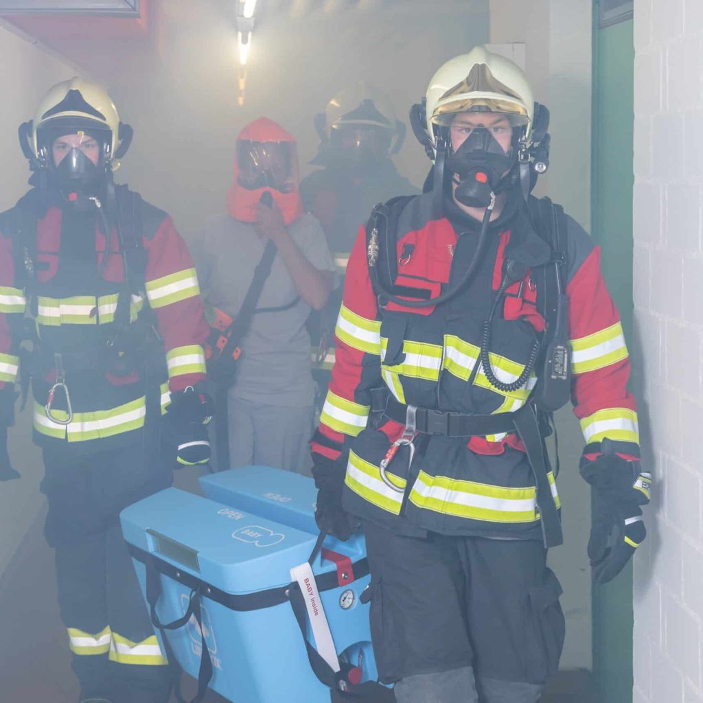 Rettungskräfte in Einsatzmontur mit Atemschutz beim Einsatz in einem Gebäude.