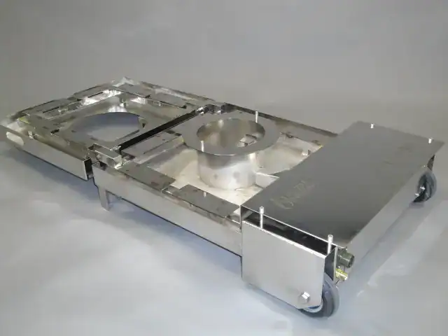 Ausschnitt eines industriellen Förderwagens mit Metallrahmen und Rollen, für effizienten Materialtransport.