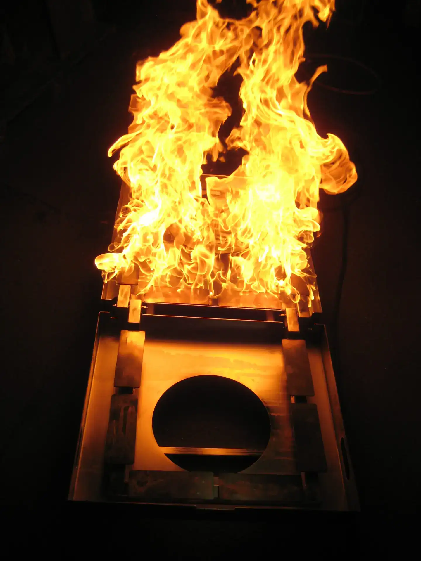 Flammen, die aus einer Holzkiste schlagen, mit dunklem Hintergrund.